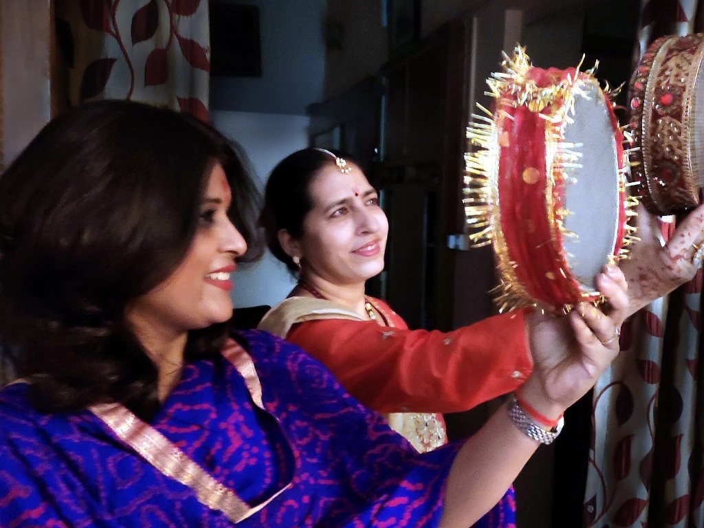 Woman looking at the moon through a sieve on Karwa Chauth