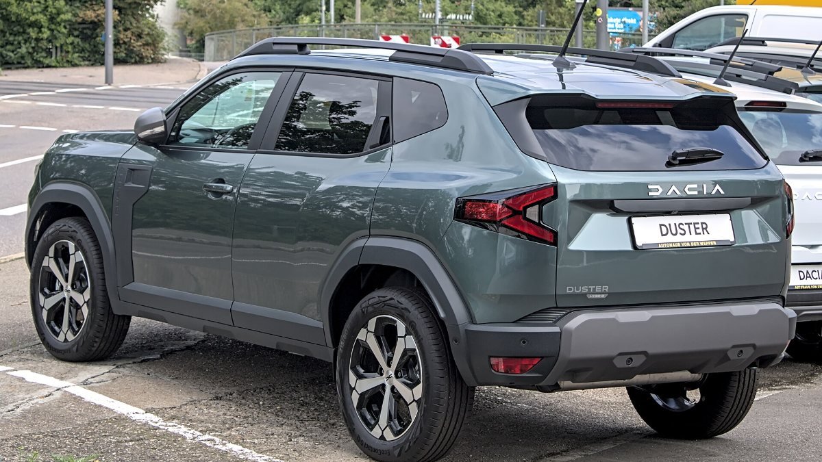 A grey-green Duster hybrid SUV parked on a street