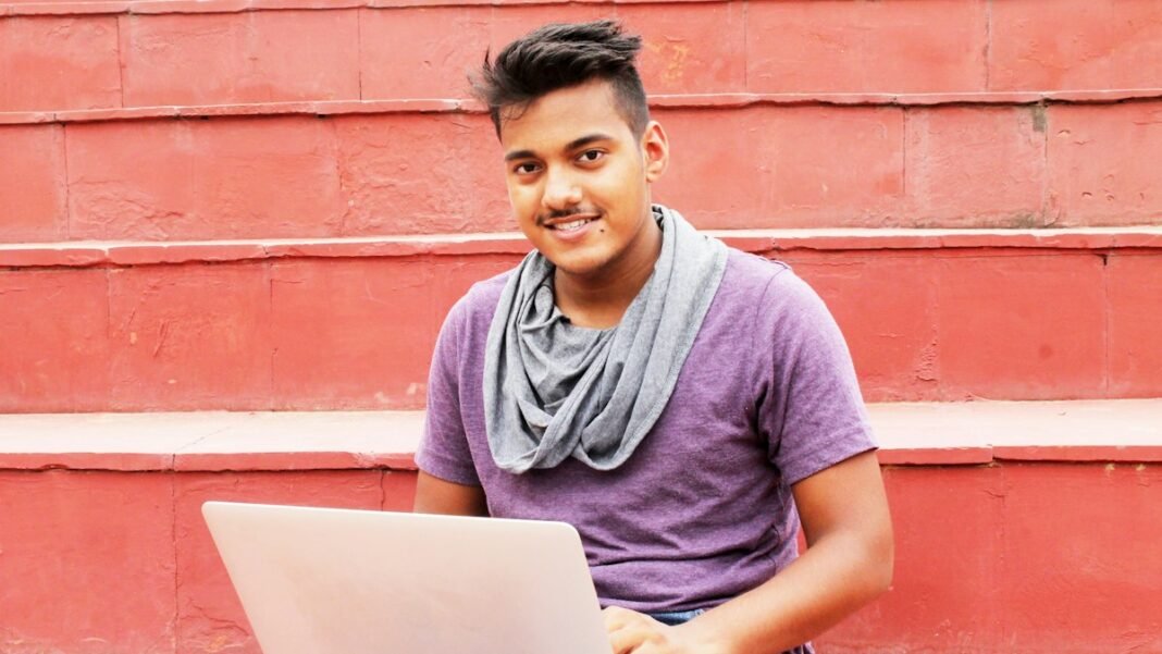 A young Indian entrepreneur smiling while working on his laptop
